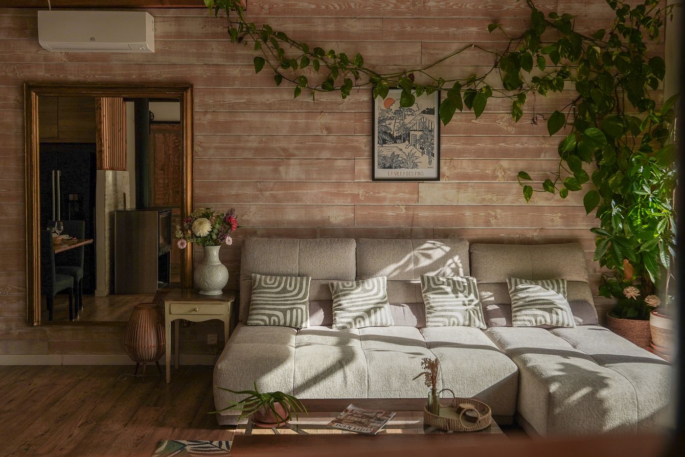 Canapé du séjour devant le mur en bois habillé de plantes grimpantes